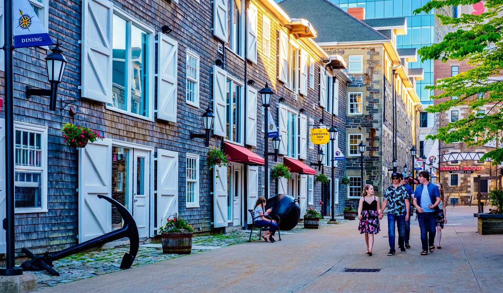 Shingled heritage buildings and an old anchor along a waterfront lane